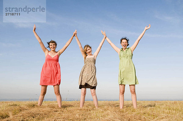 Drei Teenager-Mädchen halten die Hände hoch.