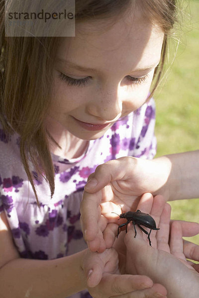 Junges Mädchen schaut auf ein Insekt