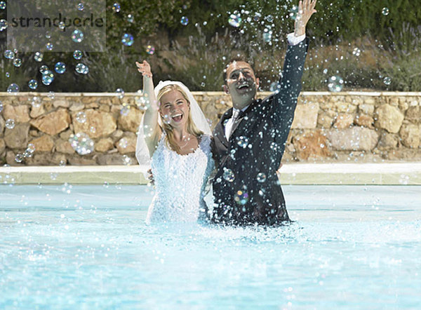 Braut und Bräutigam beim Plantschen im Pool