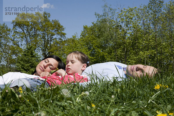Eltern und Tochter (6-7) entspannen auf der Wiese