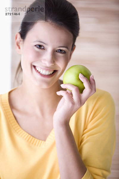 Junge Frau hält einen Apfel  lächelnd  Portrait