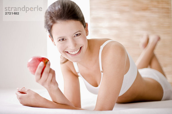 Junge Frau hält einen Apfel  lächelnd