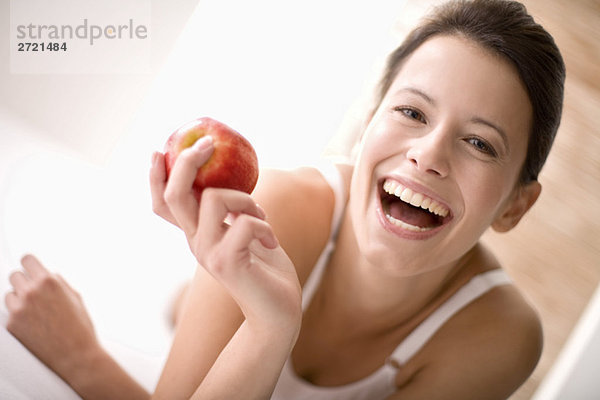Junge Frau  die einen Apfel hält  lacht