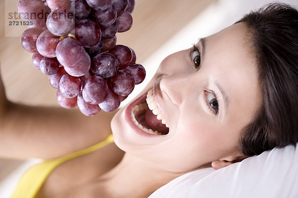 Junge Frau hält Weintrauben  lächelnd