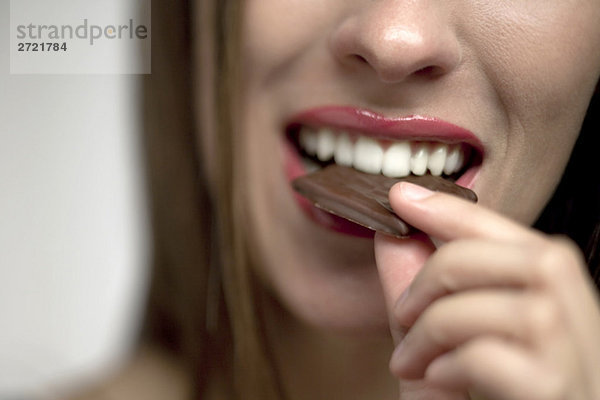 Junge Frau isst Schokoladenbonbons  Porträt
