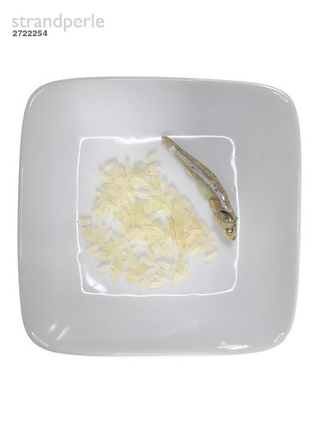 Reiskörner und getrocknete Sardellen auf Teller  erhöhte Ansicht