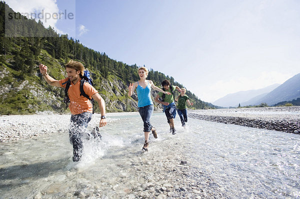 Germany  Bavaria  Tölzer Land  Young friends running through river