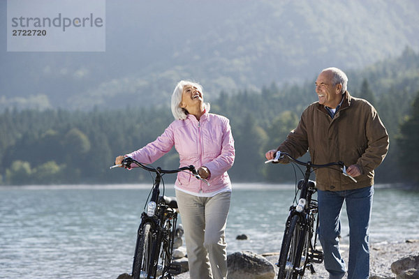 Deutschland  Bayern  Walchensee  Seniorenpaar beim Radfahren am Seeufer