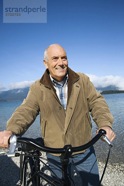 Senior Mann schiebt Fahrrad  lächelnd