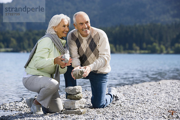 Germany  Bavaria  Walchensee  Senior couple piling up stones
