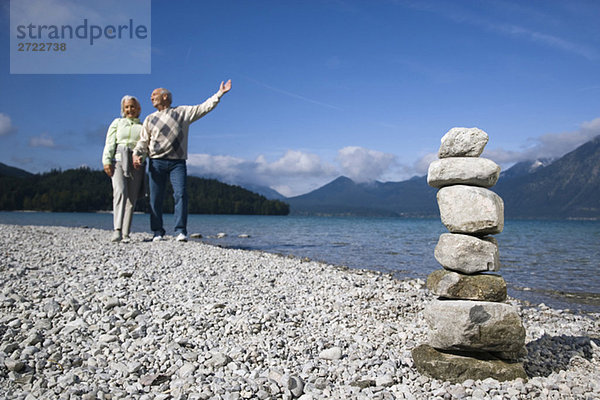 Germany  Bavaria  Walchensee  Senior couple taking a walk  stone pyramid in foreground
