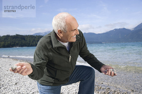 Senior man on lakeshore  skimming a stone