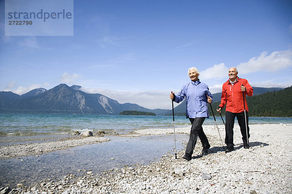 Deutschland  Bayern  Walchensee  Seniorenpaar  Nordic Walking am Seeufer