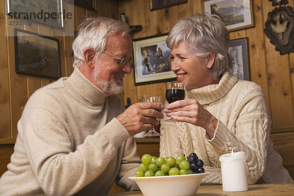 Seniorenpaar-Toasting mit Rotwein