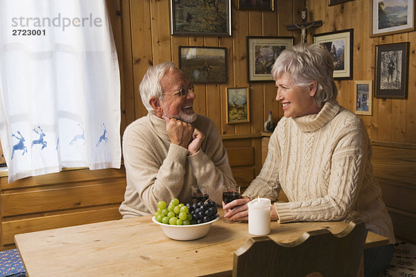 Seniorenpaar am Tisch sitzend  lächelnd