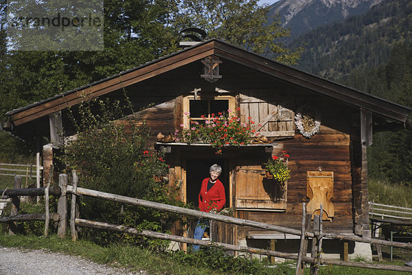 Österreich  Karwendel  Seniorin vor Blockhaus stehend  lächelnd