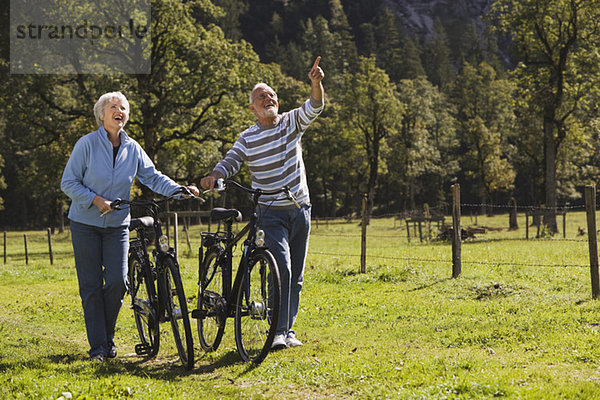 Österreich  Karwendel  Seniorenpaar schiebt Fahrräder über den Weg