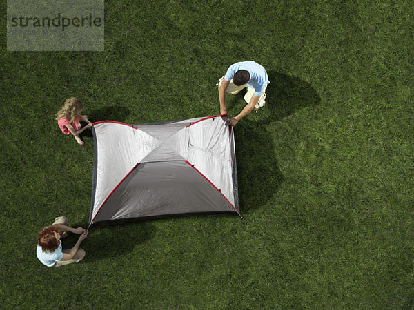 Eine junge Familie baut ein Zelt auf.
