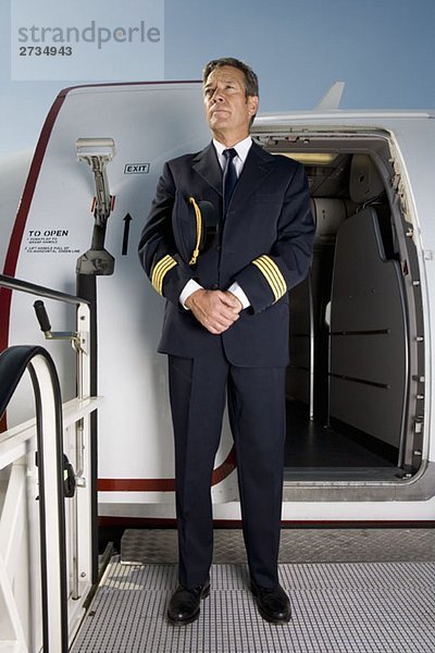 Ein Pilot  der vor der Tür eines Flugzeugs steht.