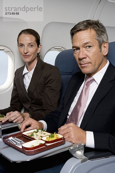 Geschäftsleute beim Essen im Flugzeug