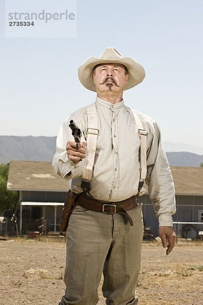 Porträt eines Cowboys  der auf seine Waffe zielt.