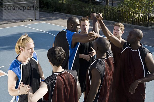 Zwei Teams von Basketballspielern beim Händeschütteln