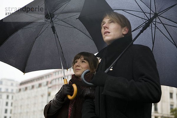 Junges Paar mit Regenschirmen