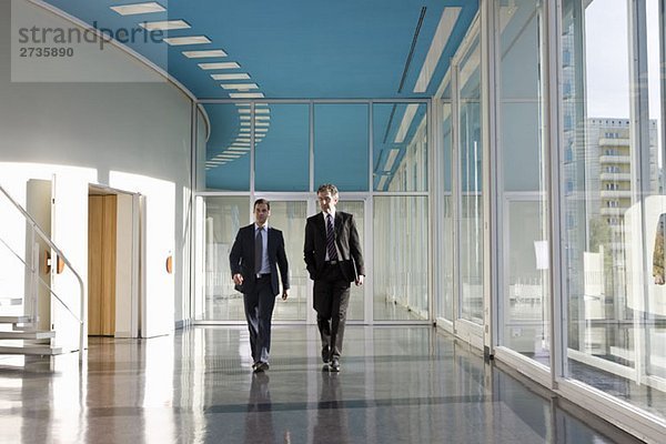 Zwei Geschäftsleute  die im Foyer eines Kongresszentrums spazieren gehen.