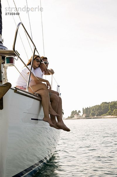 Ein Paar sitzt nebeneinander auf einer Yacht.