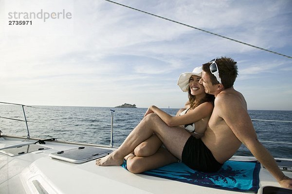 Ein Paar beim gemeinsamen Sonnenbaden auf einer Yacht