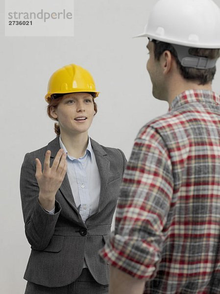 Ein Architekt im Gespräch mit einem Bauarbeiter