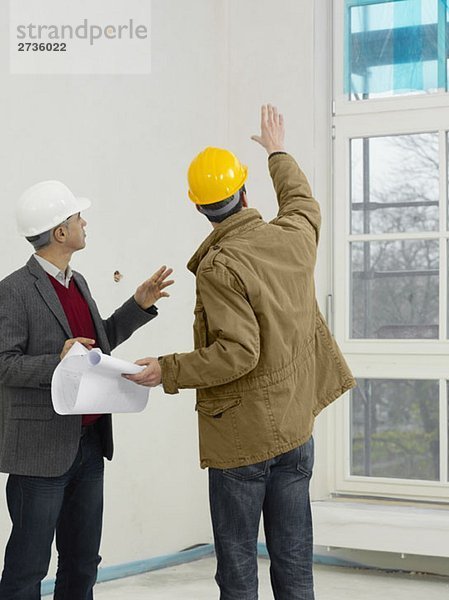 Ein Architekt im Gespräch mit einem Bauarbeiter