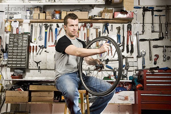 Ein Mann  der einen Fahrradreifen in einer Werkstatt repariert.