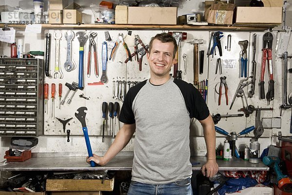 Ein Mann mit einem Schraubenschlüssel in einer Werkstatt.