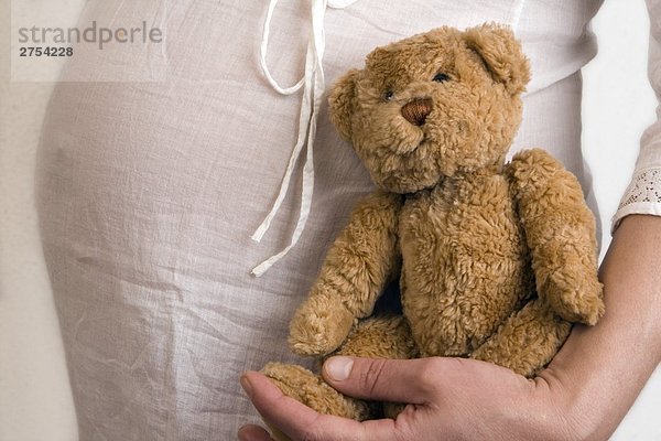 Mitte Schnittansicht schwangeren Frau hält Teddybär