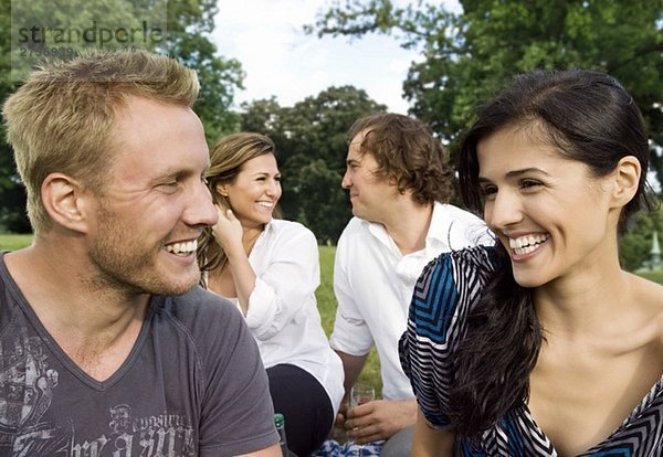 Männer und Frauen  die im Park sitzen