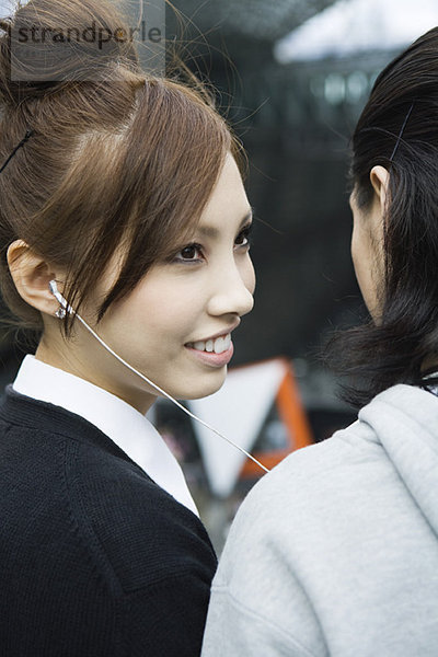Junge Frau hört Kopfhörer  lächelt Freund an  Blick in den Ausschnitt