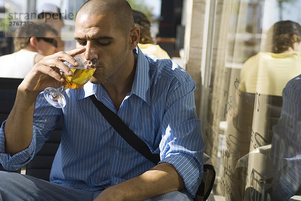 Ein Mann trinkt ein Bier in einem Straßencafé.