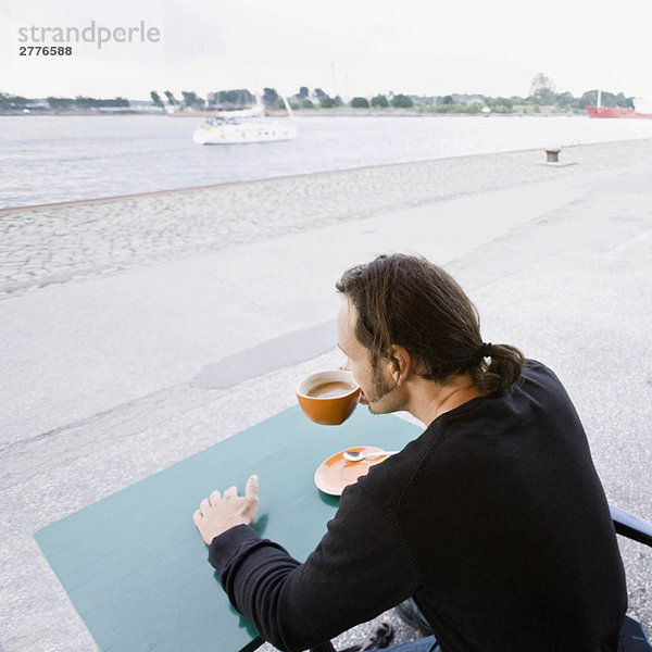 Mann sitzt in einem Café und trinkt Kaffee.