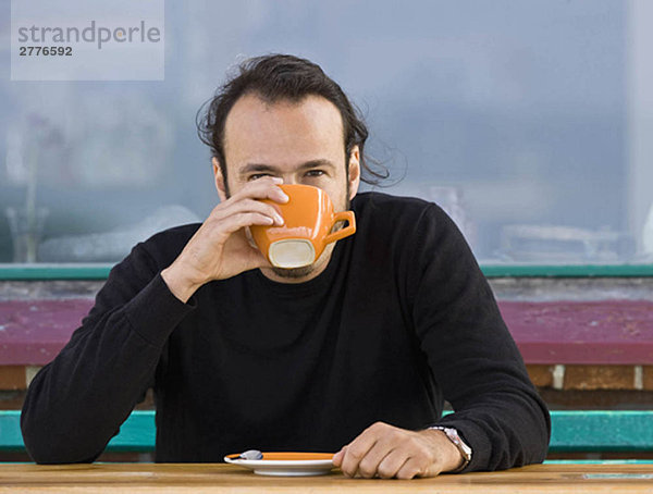 Mann sitzt in einem Café und trinkt Kaffee.