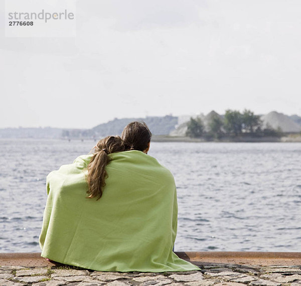 Mann und Frau starren auf einen See.