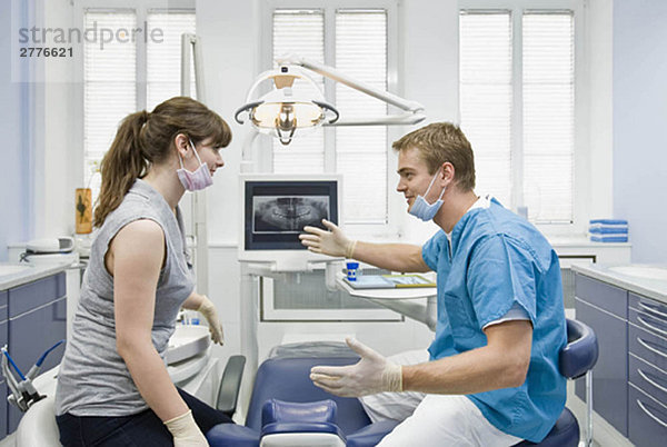 Zahnarzt im Gespräch mit der Assistentin
