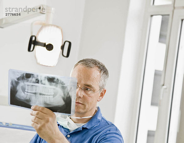 Männlicher Zahnarzt beim Betrachten von Röntgenbildern