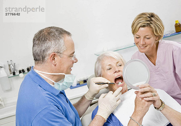 Zahnarzt und Assistentin bei der Arbeit am Patienten
