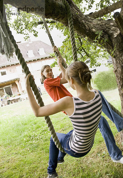 Junges Mädchen und Junge auf einer Baumschaukel