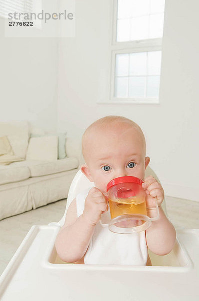Ein Porträt eines Babys  das Saft trinkt.