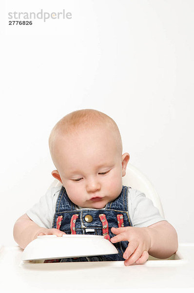Ein Baby spielt mit seinem Futternapf