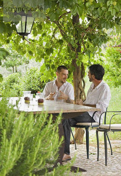 Männer entspannen sich bei Tisch im Garten