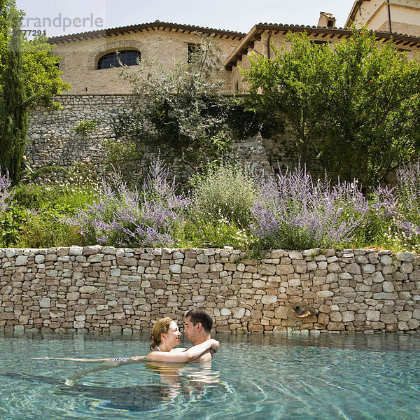 Mann und Frau umarmen sich im Pool