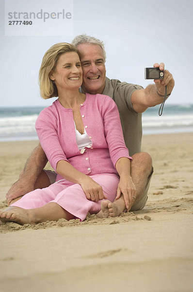 Paar beim Fotografieren am Strand